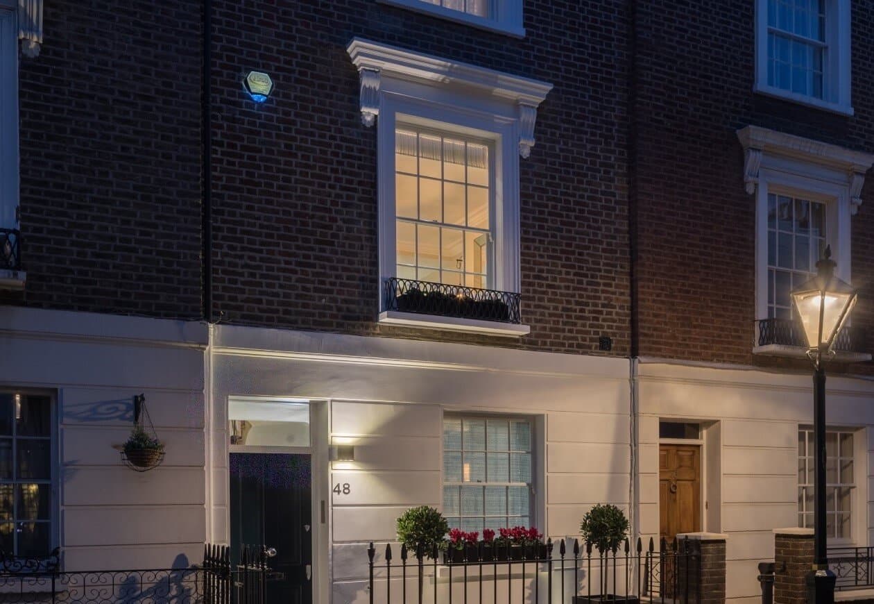 A Chelsea townhouse at dusk with a discreet security sensor fitted above the first-floor window
